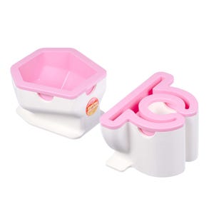 Puede incluir: Dos moldes de plástico rosa y blanco para hacer cake pops. Los moldes tienen forma de inodoro y de diamante. El molde de inodoro tiene un borde rosa y una base blanca. El molde de diamante tiene una parte superior rosa y una base blanca.
