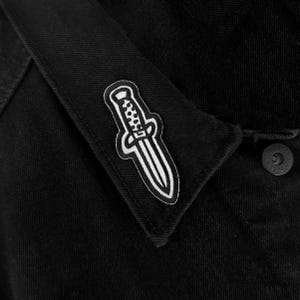 May include: A white ceramic mug with a black handle and the text "But First, Coffee" in a bold, black font. The mug is set against a blurred background, suggesting a cozy setting.