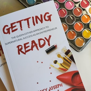 Puede incluir: Un libro titulado "Getting Ready" con texto rojo, con el nombre del autor, Nancy Joseph. La portada incluye tacones rojos, una corona dorada y lápiz labial. Un juego de pintura de acuarela con varios colores está en el fondo.