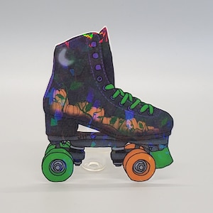 May include: A black roller skate with orange and green wheels. The skate has a holographic design with pumpkins and a crescent moon.