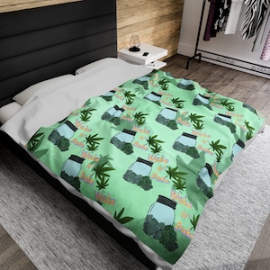 May include: Green and white patterned throw blanket with a repeating design of jars filled with green marijuana buds and the text "Wake N Bake" in orange and pink.