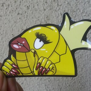 Puede incluir: Pegatina de dibujos animados amarilla de un pez con una corona, labios rojos y u&ntilde;as largas rojas. El pez lleva una corona amarilla y tiene un cuerpo amarillo con l&iacute;neas negras.