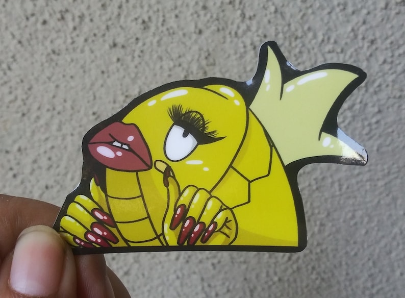 Puede incluir: Pegatina de dibujos animados amarilla de un pez con una corona, labios rojos y u&ntilde;as largas rojas. El pez lleva una corona amarilla y tiene un cuerpo amarillo con l&iacute;neas negras.