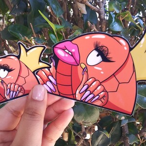 Puede incluir: Dos pegatinas de peces de dibujos animados de color rojo y naranja con coronas amarillas y u&ntilde;as largas de color rosa y morado. Los peces tienen ojos grandes y labios rosas.