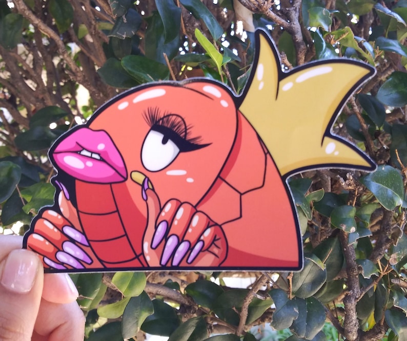 Puede incluir: Una pegatina de dibujos animados roja y amarilla de un personaje con pesta&ntilde;as largas, labios rosados y u&ntilde;as largas. El personaje lleva una corona.
