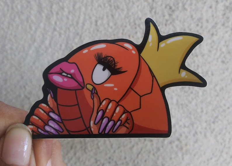 Puede incluir: Un langostino de dibujos animados rojo y naranja con u&ntilde;as largas de color p&uacute;rpura y una corona amarilla. El langostino lleva maquillaje y tiene una boca rosa de puchero.