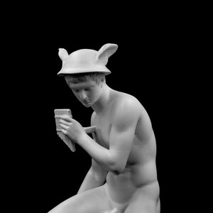 Puede incluir: Una estatua de yeso blanco de una persona que lleva un casco alado y sostiene un objeto peque&ntilde;o en su mano.