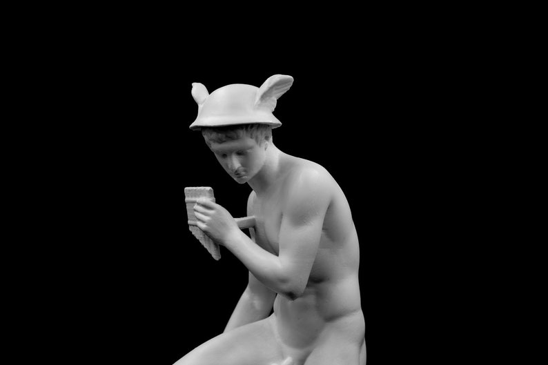 Puede incluir: Una estatua de yeso blanco de una persona que lleva un casco alado y sostiene un objeto peque&ntilde;o en su mano.