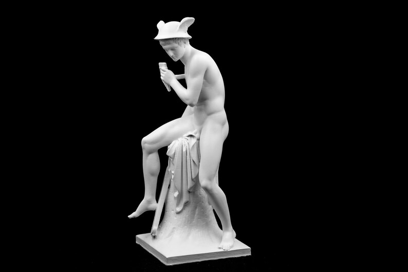 Puede incluir: Una estatua de m&aacute;rmol blanco de una figura masculina desnuda sentada en una roca, sosteniendo un bast&oacute;n en su mano derecha. La figura lleva un casco alado y una tela drapeada.