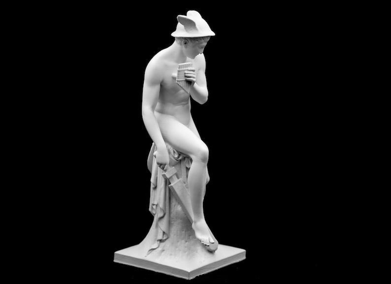 Puede incluir: Una estatua de m&aacute;rmol blanco de una figura sentada tocando una flauta de pan. La figura lleva un casco alado y una tela drapeada. La estatua est&aacute; sobre una base cuadrada.