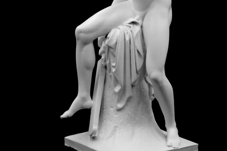 Puede incluir: Una escultura de yeso blanco de una figura con una pierna doblada y la otra recta. La figura lleva una tela drapeada y est&aacute; de pie sobre un pedestal.