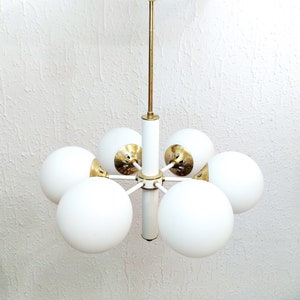 K&ouml;nnte beinhalten: Ein wei&szlig;er und goldener sechsarmiger Kronleuchter mit runden wei&szlig;en Glasschirmen.