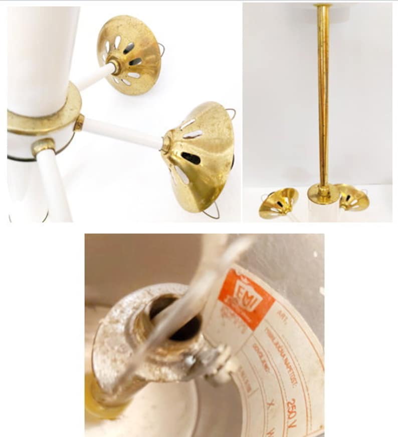 K&ouml;nnte beinhalten: Eine wei&szlig;e und goldene Deckenleuchte mit drei Armen und drei runden, goldfarbenen Schirmen. Die Leuchte hat ein wei&szlig;es Kabel und eine wei&szlig;e Deckenmontage. Die Schirme haben ein dekoratives Muster aus kleinen L&ouml;chern. Die Leuchte ist seitlich mit "EMI 250V" beschriftet.