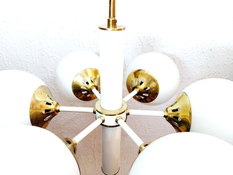 K&ouml;nnte beinhalten: Ein wei&szlig;er und goldener Mid-Century-Modern-Kronleuchter mit sechs kugelf&ouml;rmigen Schirmen.