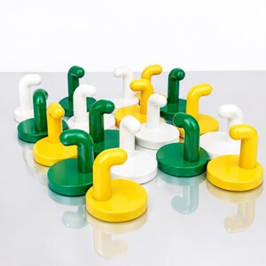 May include: A collection of wall hooks in a glossy finish, featuring a circular base and a curved, J-shaped arm. The hooks are arranged in a group and come in three distinct solid colors: bright yellow, forest green, and crisp white.