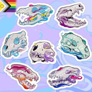 Könnte beinhalten: Eine Sammlung von sieben Aufklebern mit stilisierten Illustrationen von Tierschädeln. Jeder Schädel ist weiß mit farbenfrohen Akzenten in Rosa, Blau, Gelb und Lila. Der Hintergrund ist helllila mit einem wellenförmigen Muster. Eine Pride-Flagge befindet sich oben links.