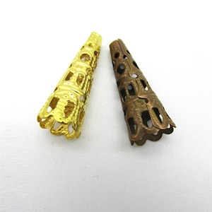 May include: Two metal cone-shaped bead caps. One is gold-colored, the other is bronze. Both have a filigree design with openwork patterns and a scalloped edge. These decorative bead caps are used in jewelry making.