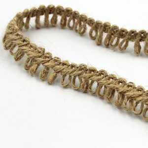 May include: A close-up of natural brown jute trim with a looped design. The trim is made of natural fibres and has a rustic look.