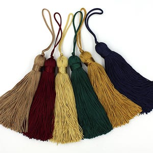 May include: Six tassel ornaments in a variety of colours, including beige, burgundy, gold, green, and navy blue. The tassels are made from soft, silky threads and have a loop at the top for hanging.