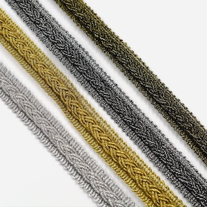 May include: Four braided trim cords in gold, silver, black, and bronze. The cords are woven with a decorative pattern and have a metallic sheen.