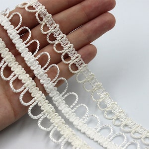 May include: Three white crocheted trims with looped edges. The trims are arranged in a row, with the largest trim at the top and the smallest trim at the bottom.