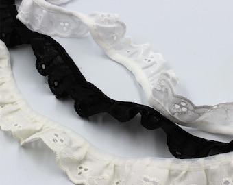 Peut inclure: Gros plan sur trois garnitures de dentelle à volants blanches, noires et blanc cassé. La dentelle présente un bord festonné et de petits motifs découpés décoratifs. Les garnitures sont disposées en diagonale, mettant en valeur leur texture et leur design.