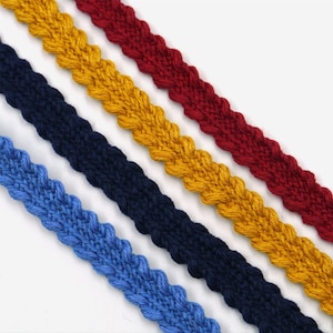 Può includere: Quattro colori diversi di cordoncino intrecciato, blu, blu navy, giallo e rosso. Il cordoncino è spesso e ha una superficie testurizzata.