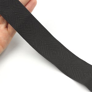 May include: Black elastic trim with a geometric diamond pattern. The trim is approximately 2.5 cm wide.