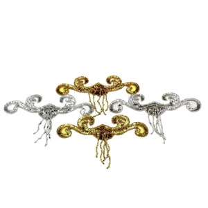 May include: Three decorative embellishments with a swirling design and dangling beads. The embellishments are silver, gold, and bronze.
