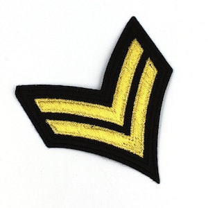 May include: A black fabric patch with two gold chevron stripes. The patch is shaped like a point.