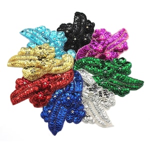 Pode incluir: Conjunto de remendos de tecido em forma de folha cobertos com lantejoulas coloridas. Os remendos são em tons turquesa, dourado, vermelho, azul, prateado, verde e rosa.