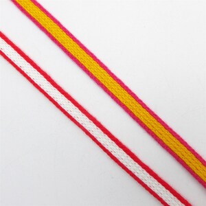 May include: Two pieces of ribbon, one pink with a white stripe and one yellow with a pink stripe.