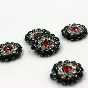 May include: Four circular decorative buttons featuring a central red rhinestone surrounded by a ring of clear white rhinestones and an outer border of dark green rhinestones, all set in a silver-toned metal base with a faceted finish.
