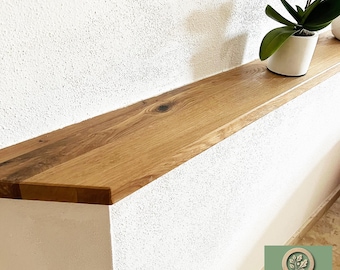 Puede incluir: Una estantería de madera clara montada en una pared blanca con una pequeña planta de orquídea en maceta en la parte superior. La estantería está inclinada y tiene una veta de madera natural. El texto "STEINHOLZ" es visible en la esquina inferior derecha de la imagen.