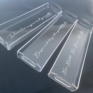 May include: Three rectangular clear acrylic trays with integrated handles. Each tray features white cursive text: Don't let anyone steal your sparkle, Begin each day with a grateful heart, and Be Bold Be Brave Be You. The trays are arranged diagonally.
