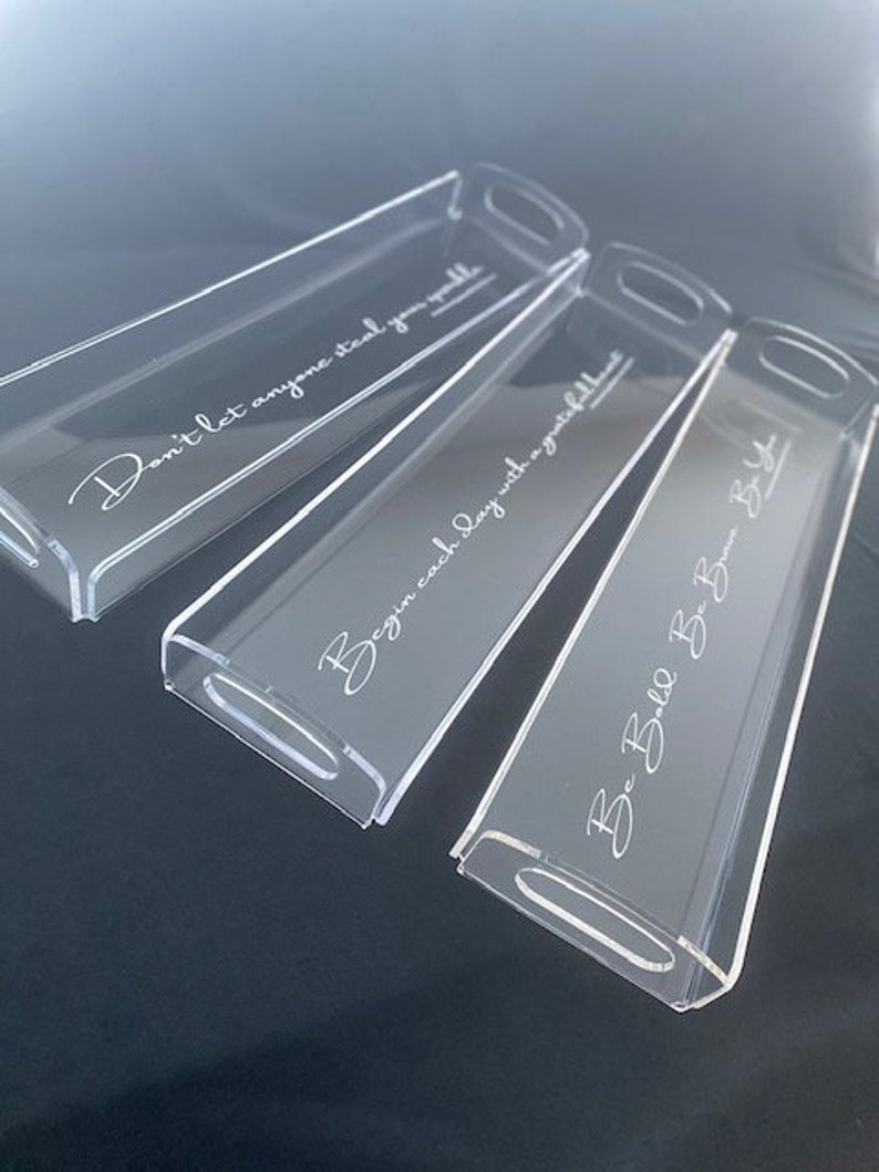 May include: Three rectangular clear acrylic trays with integrated handles. Each tray features white cursive text: Don't let anyone steal your sparkle, Begin each day with a grateful heart, and Be Bold Be Brave Be You. The trays are arranged diagonally.