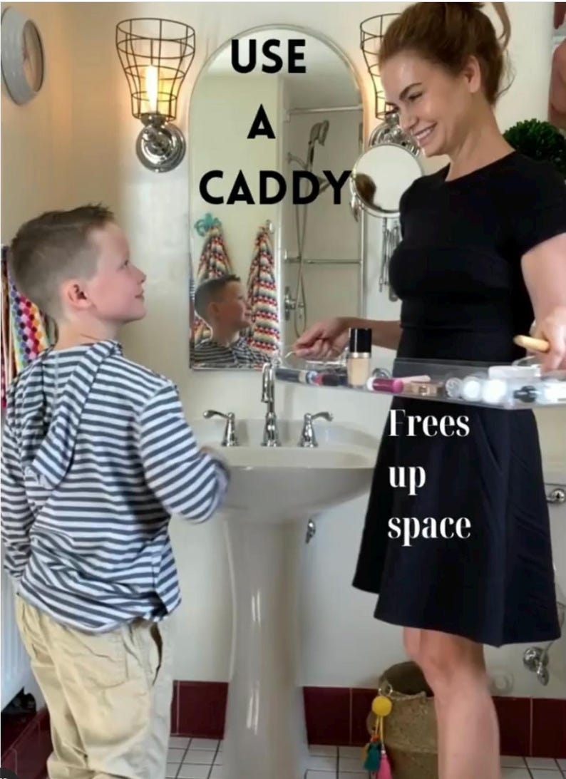 May include: A clear acrylic bathroom caddy holding various cosmetic bottles and tubes. The text USE A CADDY is printed in black above the caddy, and the text Frees up space is printed in white below the caddy, highlighting its storage function.