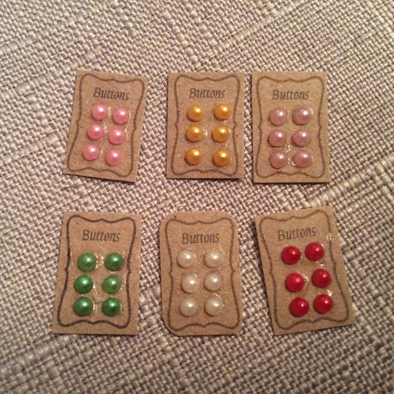 May include: Six cards with the word "Buttons" printed on them. Each card has six small round buttons in different colours: pink, yellow, white, green, and red.