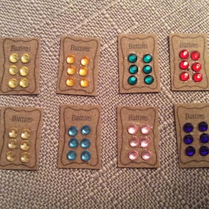 May include: Eight cards with the word "Buttons" printed on them. Each card has six small, round, colourful buttons. The colours of the buttons are yellow, orange, teal, red, light yellow, blue, pink, and dark blue.