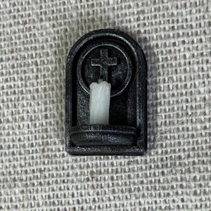 Puede incluir: Aplique de pared de metal negro con una vela blanca y una cruz en un círculo sobre el portavelas.