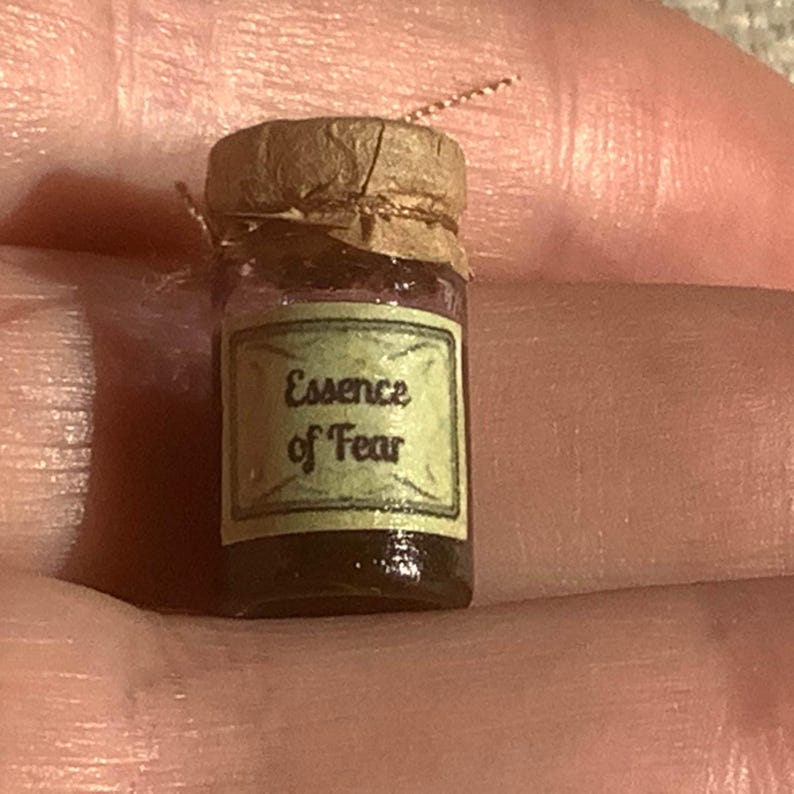 May include: A small glass jar with a cork lid and a label that reads "Essence of Fear". The jar is filled with a dark liquid.