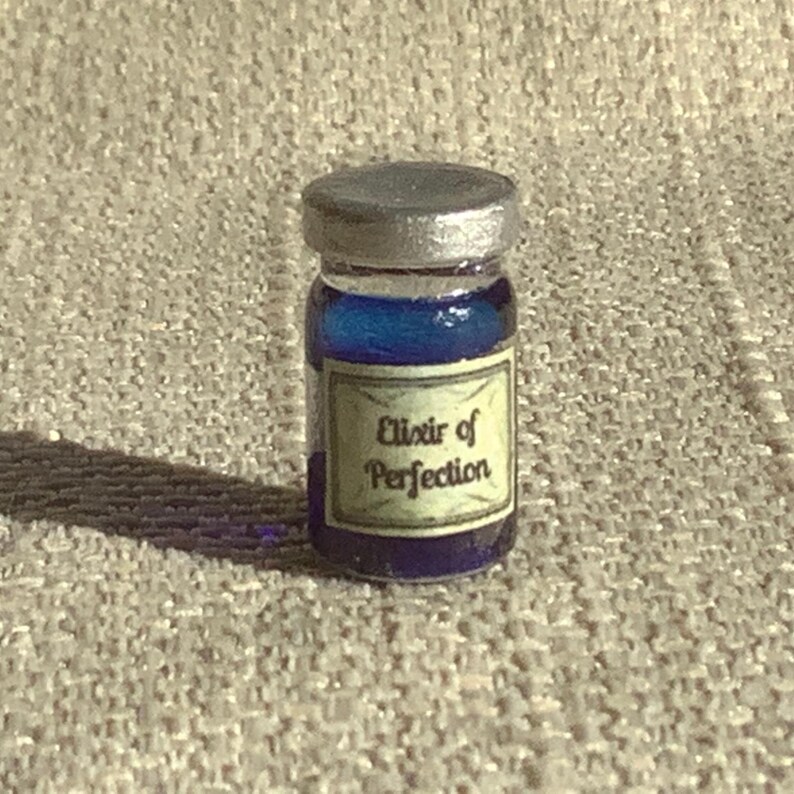 May include: A small glass bottle with a silver lid filled with a blue liquid. The bottle has a label that reads "Elixir of Perfection".