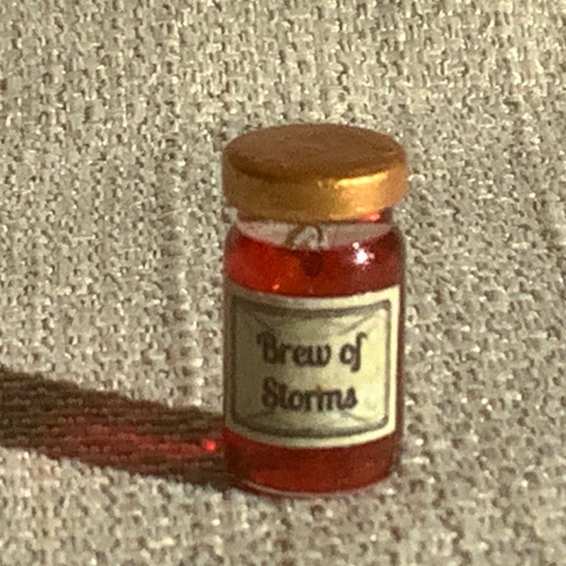 May include: A small glass jar with a gold lid filled with a red liquid. The label on the jar reads "Brew of Storms".