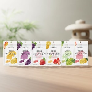 May include: Six packets of Japanese gummy sweets are displayed on a wooden surface. Each packet features a different fruit illustration, including grapes, strawberries, and lemons. The text on the packets is in Japanese.