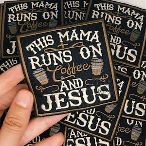 Op de afbeelding: Een vierkante zwarte geborduurde patch met de witte en gouden tekst THIS MAMA RUNS ON Coffee AND JESUS. Het ontwerp bevat twee kleine koffiebeker-iconen met gouden en grijze details, allemaal omrand door een dunne gouden gestikte rand.