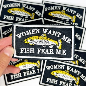 May include: Black rectangular patch with white border and text "WOMEN WANT ME FISH FEAR ME" in white. A yellow and white fish graphic is centered above the text. Multiple patches are visible.