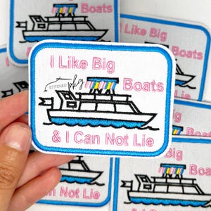 May include: Embroidered patch with a white background and a blue border. The patch features a boat design with the text "I Like Big Boats & I Can Not Lie" in pink and black. The boat has a blue hull and a rainbow-colored top.