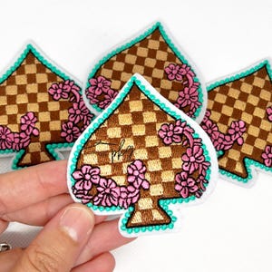 May include: A white ceramic mug with a black handle and the text "But First, Coffee" in a black, handwritten-style font. The mug is on a white surface.