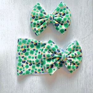 May include: A green, white and yellow headband with a shamrock pattern and a matching bow. The headband is made of soft, stretchy fabric and is perfect for adding a touch of Irish charm to any outfit.