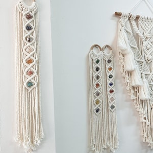 May include: Three macrame wall hangings with colourful stones woven into the design. The hangings are made with white cotton cord and have a fringe at the bottom.